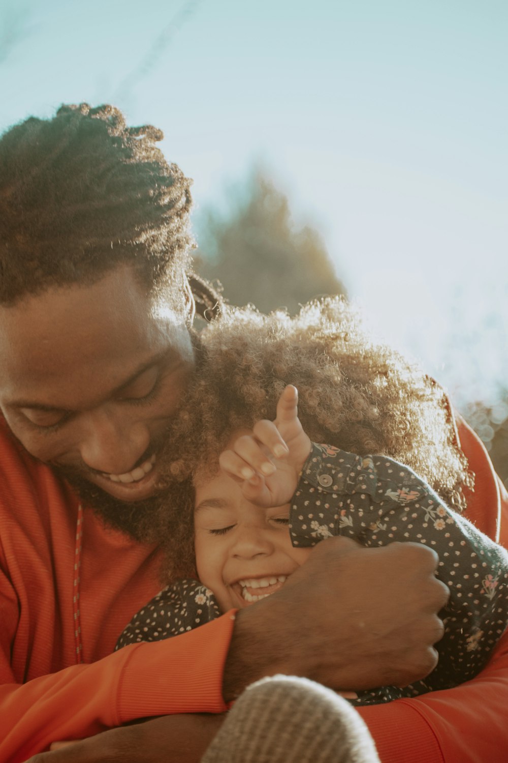 A father hugging his laughing young daughter in golden sunlight